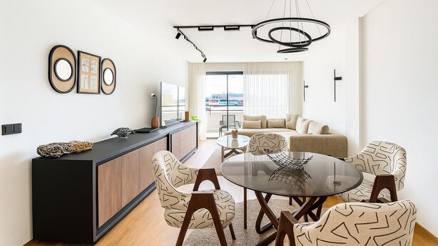 A modern living room with a round glass table, patterned chairs, a sofa, and a view of the city through large windows. - Bright studio with balcony & sea view, near port (CASABLANCA)