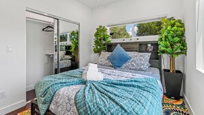 Un dormitorio moderno con cama, armario y dos plantas en macetas.