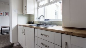A modern kitchen with white cabinets, a wooden countertop, and a window above the sink. - The Royal Residence - Sorley Steet, 2 minutes to Royal Sunderland Hospital (sunderland)
