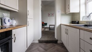 A narrow kitchen with white cabinets, a wooden countertop, and a herringbone-patterned floor. - The Royal Residence - Sorley Steet, 2 minutes to Royal Sunderland Hospital (sunderland)