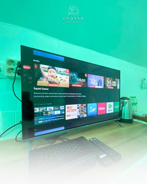 A television displaying a Netflix interface with various shows and a keyboard in front.