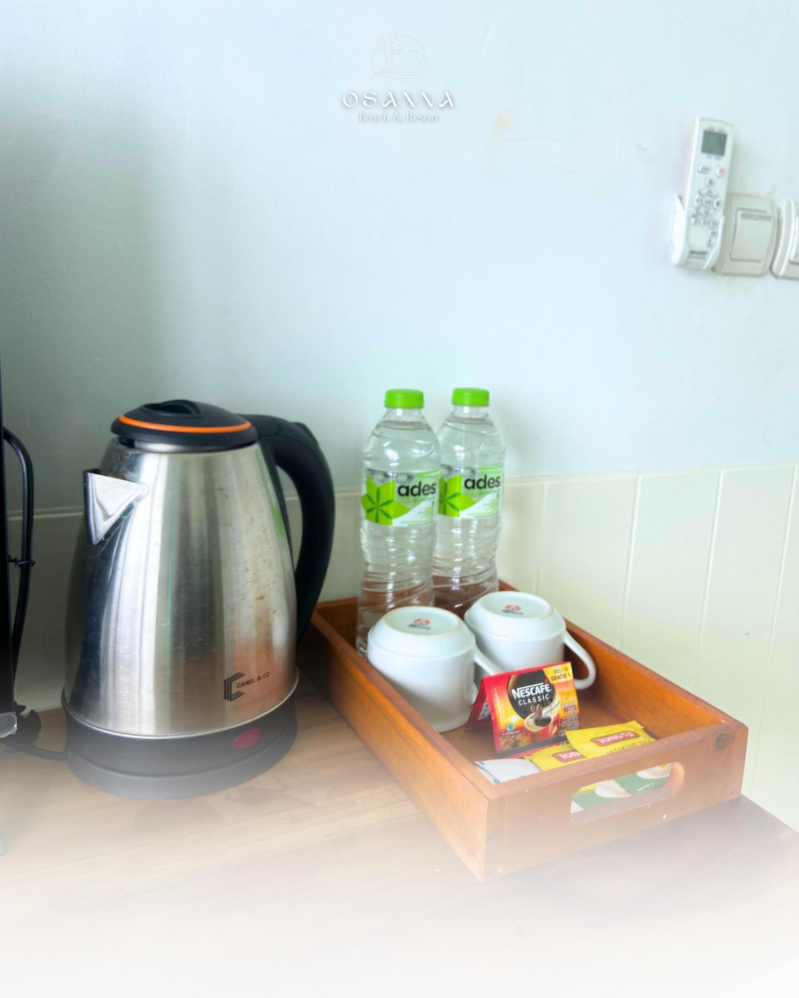 A kitchen counter with a kettle, water bottles, cups, and a tray with coffee pods.