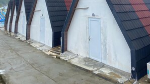 A row of identical buildings with sloped roofs and white doors, likely part of a caravan or camping site. - OSANNA BEACH RESORT (Gunturharjo)