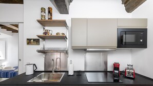 A modern kitchen with a stainless steel sink, a black microwave, and a red toaster. - Banchi Prestige - Castel Sant'Angelo (Roma)