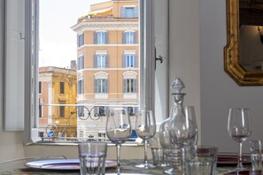 Una habitación con vistas a edificios a través de una ventana, una mesa con copas de vino y un espejo en la pared.