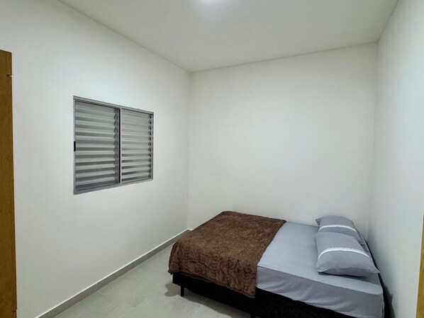 A small, single-bed room with a window and a door.