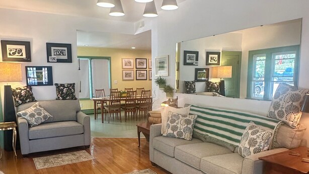 A living room with a sofa, a coffee table, and a dining area with chairs and a table. - Spacious Vintage Getaway. Walkable! (Casper)