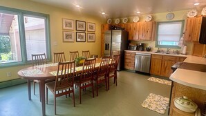 A kitchen with wooden cabinets, a stainless steel refrigerator, a dishwasher, and a dining area with a table and chairs. - Spacious Vintage Getaway. Walkable! (Casper)