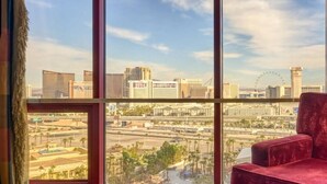 Ein Zimmer mit großem Fenster und Blick auf eine Stadtansicht, darunter ein Riesenrad und verschiedene Gebäude.