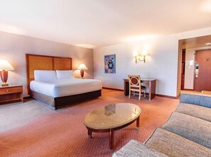 Una habitación de hotel con cama, escritorio, silla, mesita y sofá.