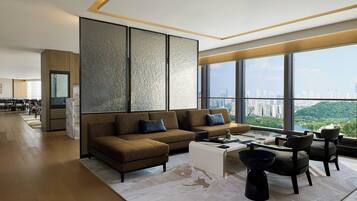 Una sala de estar moderna con un sofá grande, una mesa de centro y sillas, un ventanal con vistas a la ciudad y piso de madera.