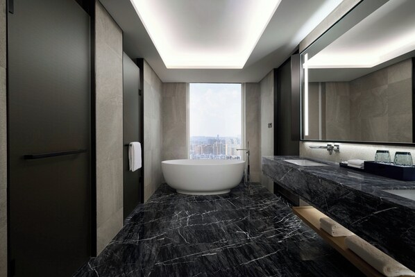 A modern bathroom with a freestanding bathtub, a large mirror, and a view of the city.