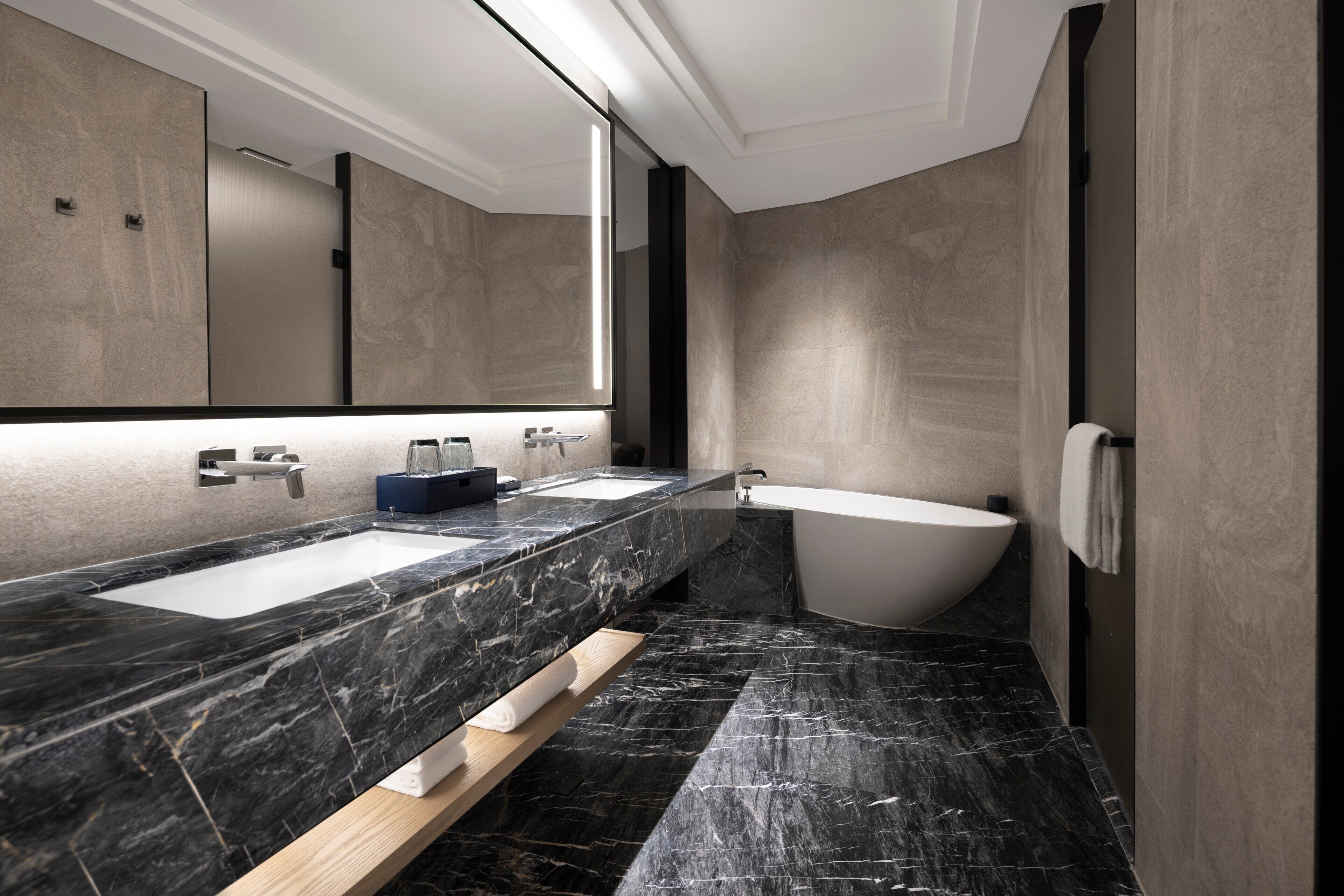Un baño moderno con dos lavamanos, una bañera y un espejo grande.