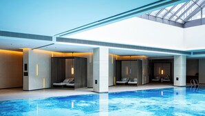 Piscina interior moderna com áreas de estar e claraboia.
