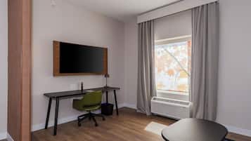 Une chambre d’hôtel équipée d’un bureau, d’une chaise et d’une grande fenêtre avec des rideaux.