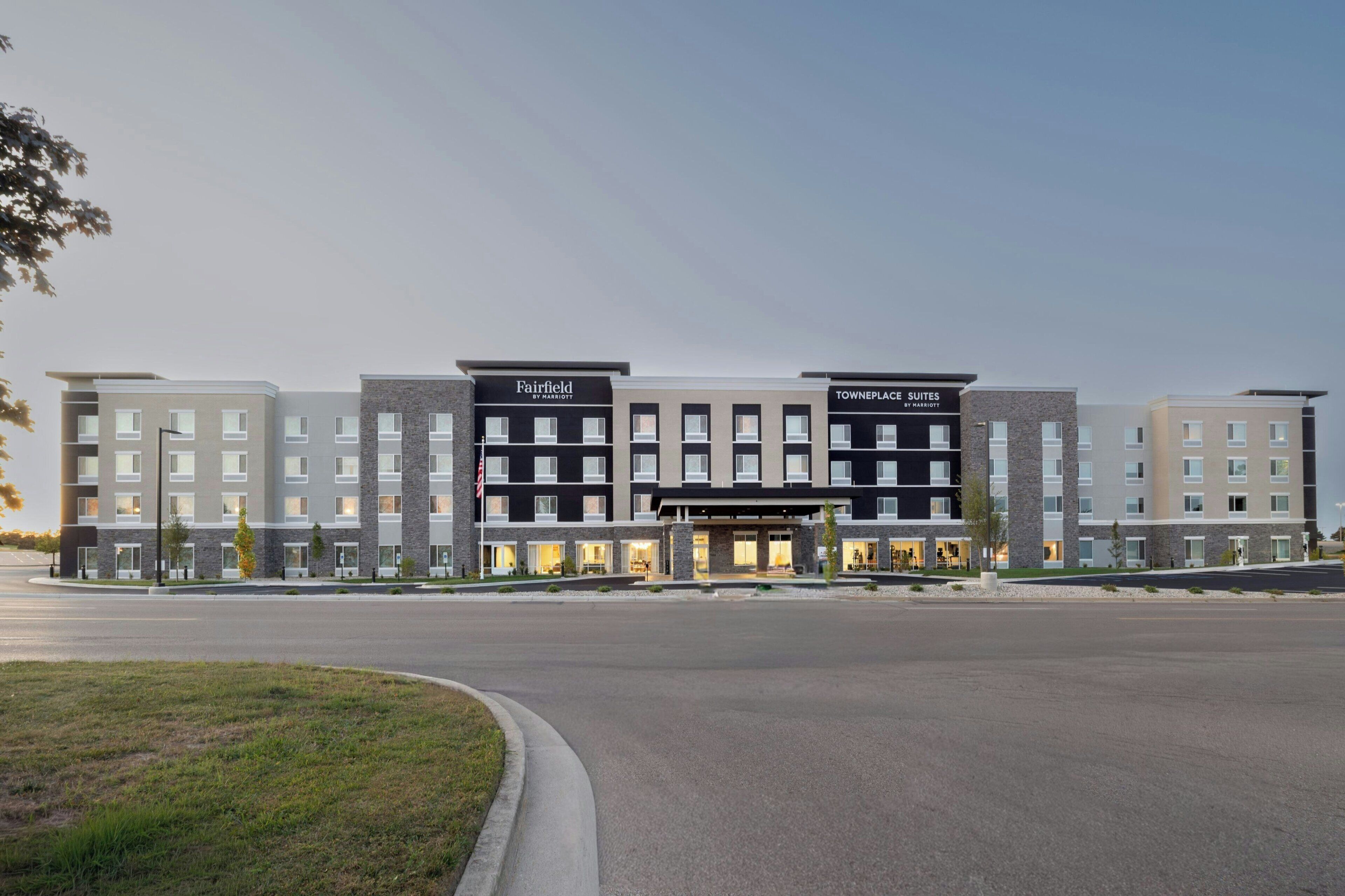 Un hotel de varios pisos con un diseño moderno, que presenta una entrada central y múltiples habitaciones.
