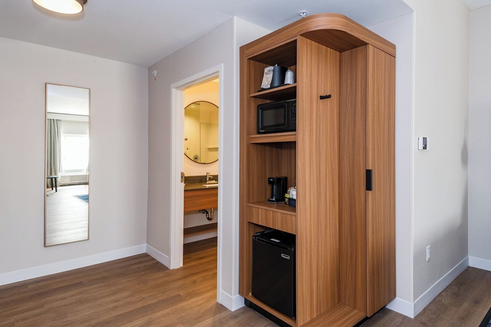 A modern kitchen with built-in appliances, a wooden cabinet, and a mirror.