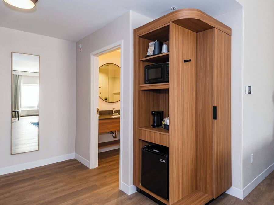 A modern kitchen with built-in appliances, a wooden cabinet, and a mirror.