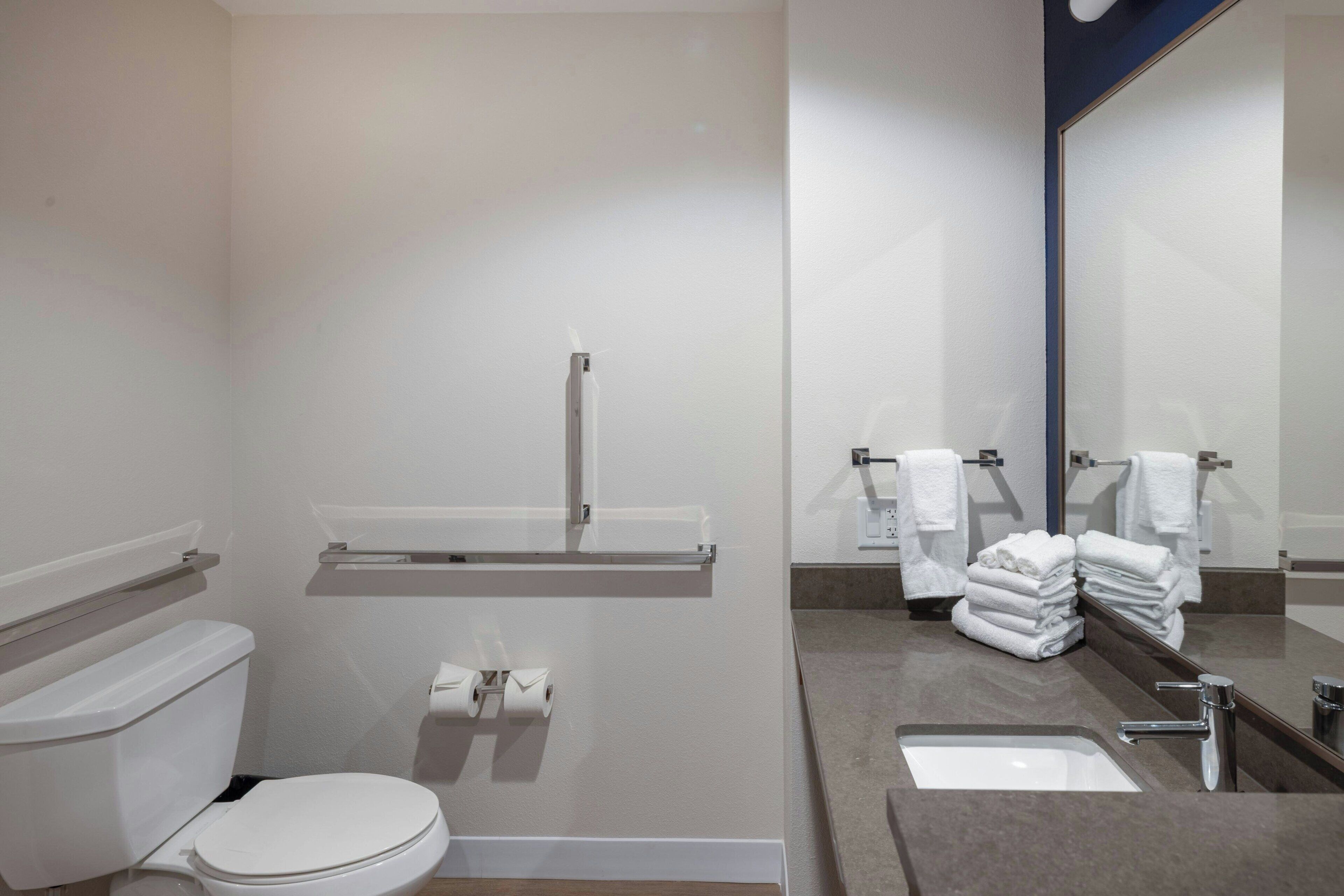 A modern bathroom with a toilet, a sink, a mirror, and a towel rack.