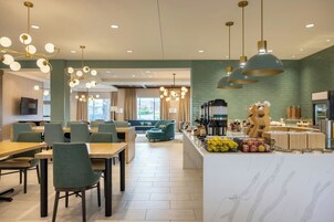 Un comedor moderno con mesas, sillas y una barra con comida y bebidas.