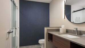 A modern bathroom with a glass shower enclosure, a white toilet, and a vanity with a mirror and sink. - Fairfield Inn & Suites Huntsville Madison (Madison)