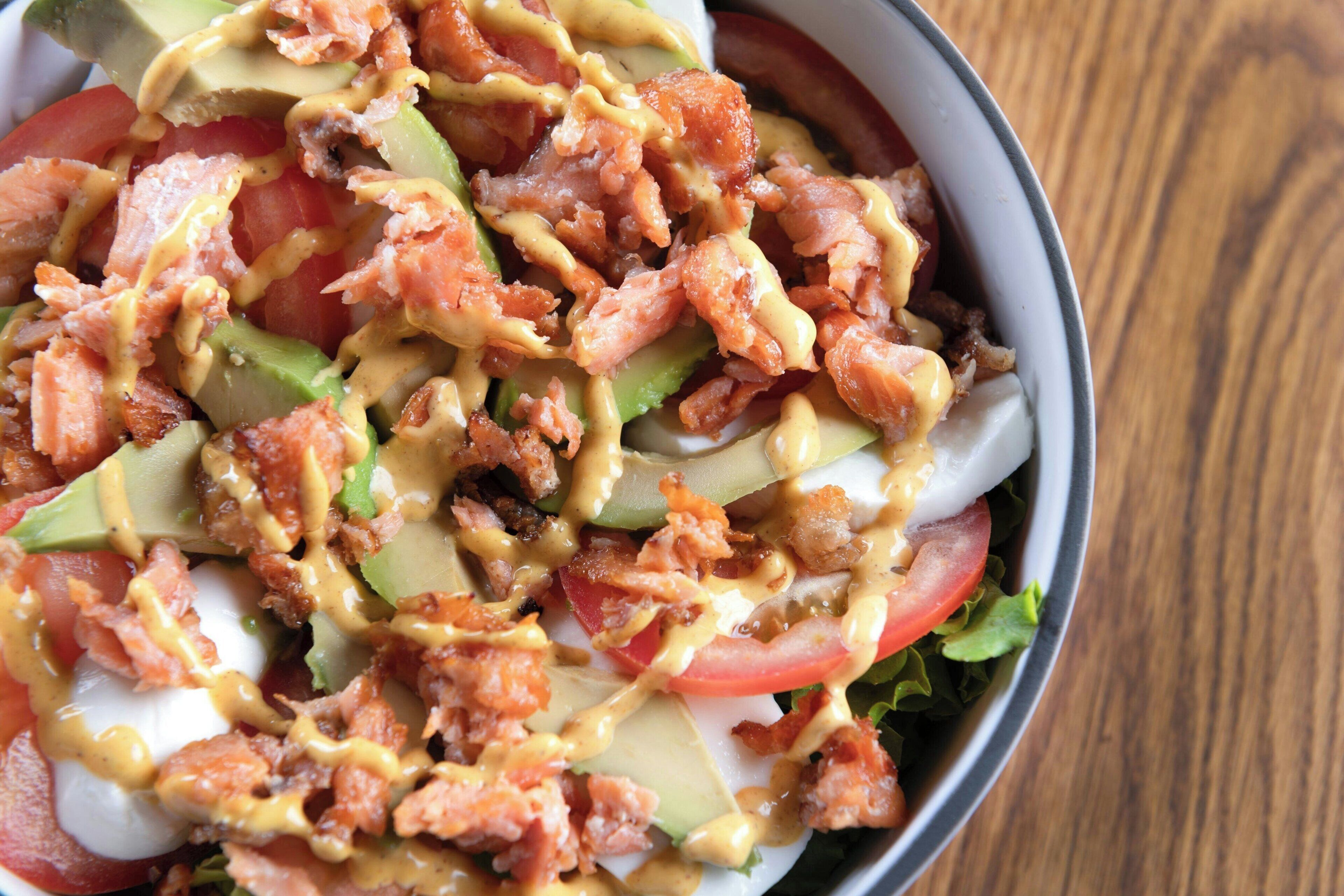Ein Salat mit Avocado, Speck und cremigem Dressing.