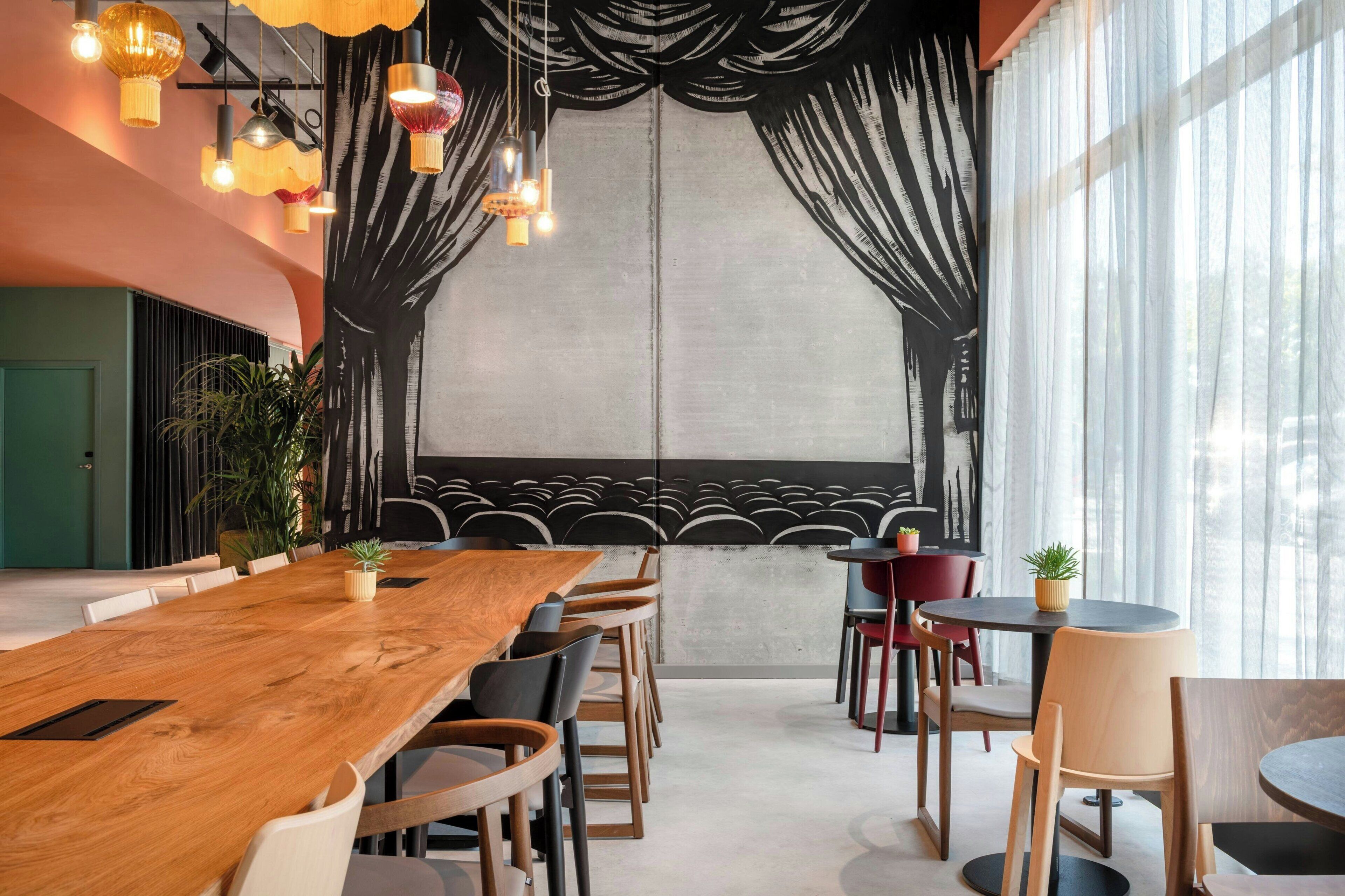 Ein modernes Restaurant mit einem langen Holztisch, mehreren Stühlen und hängenden Pendelleuchten.