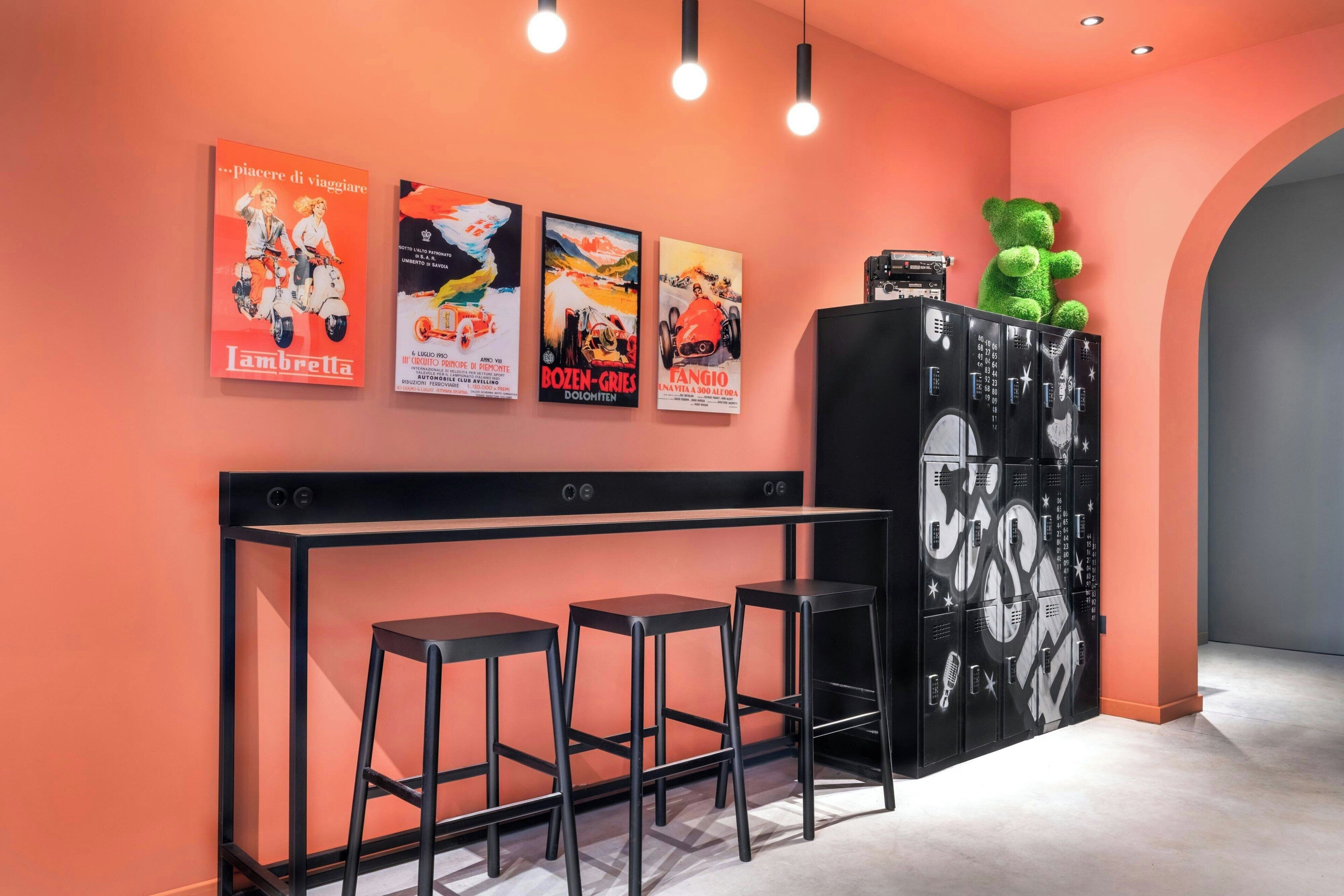 A bar area with three stools, a black cabinet with decorative elements, and three movie posters on the wall.