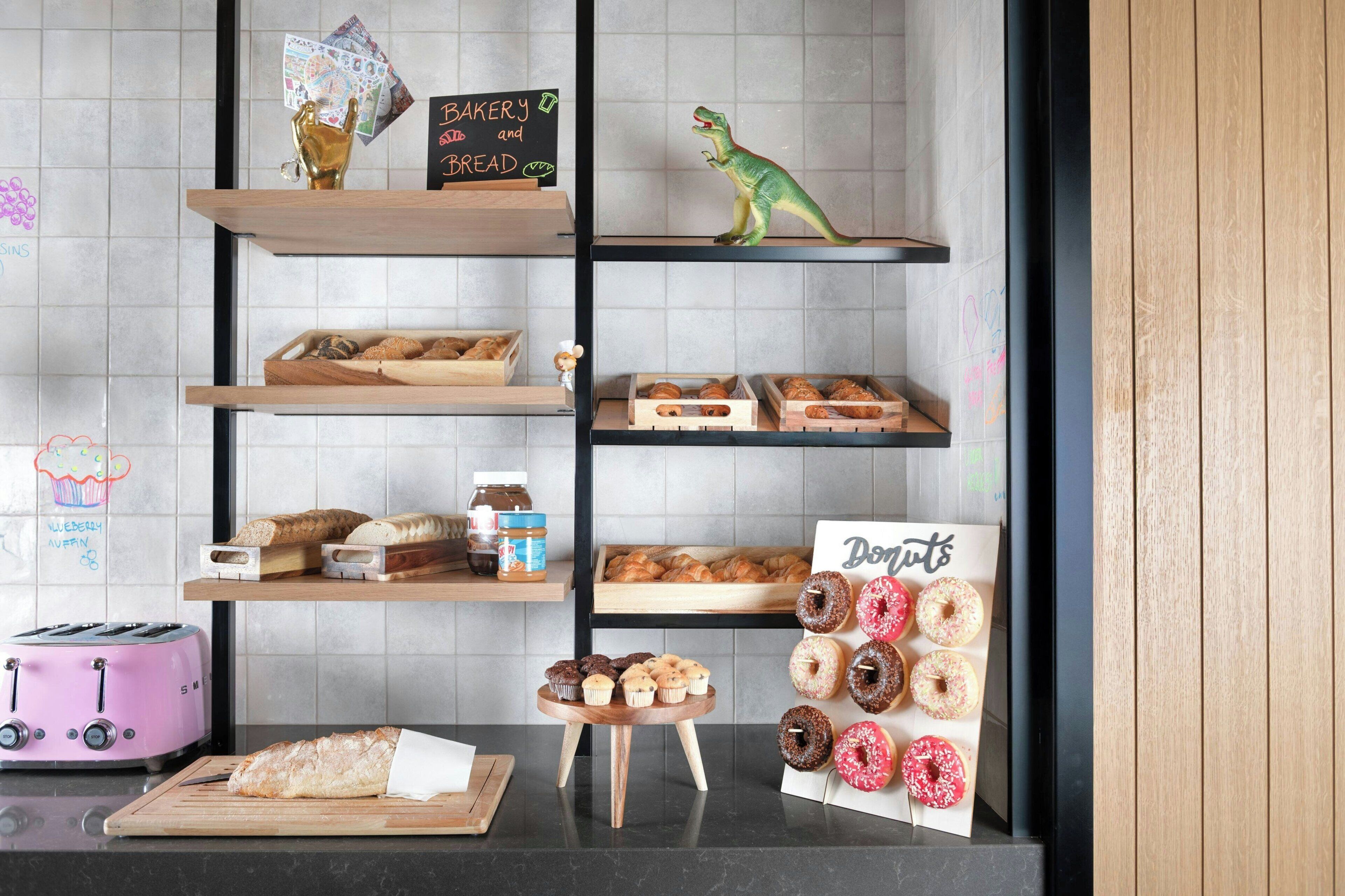 A bakery display with various baked goods and a dinosaur figure.
