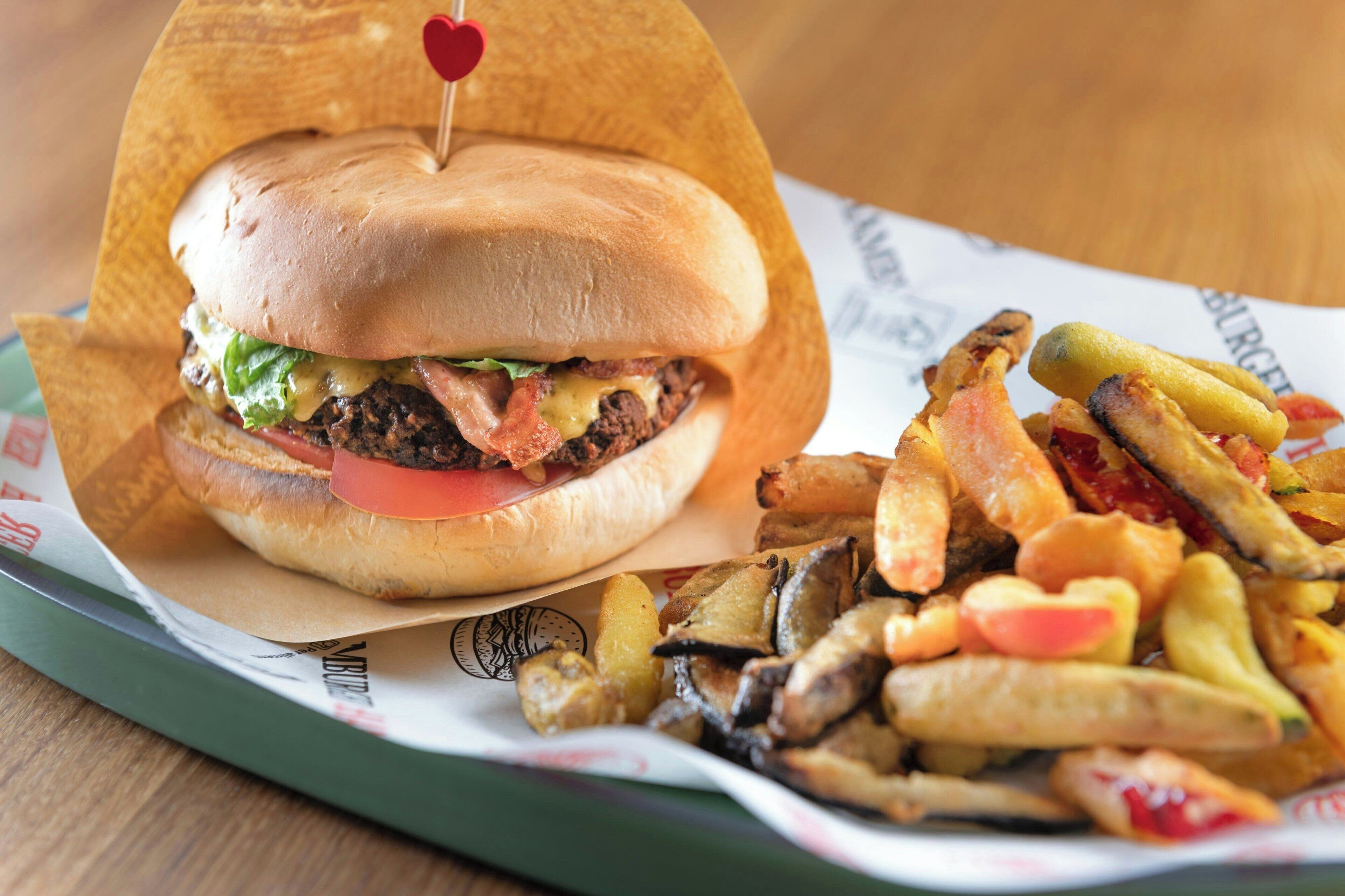A burger with a heart-shaped pick on top, accompanied by a side of fries.