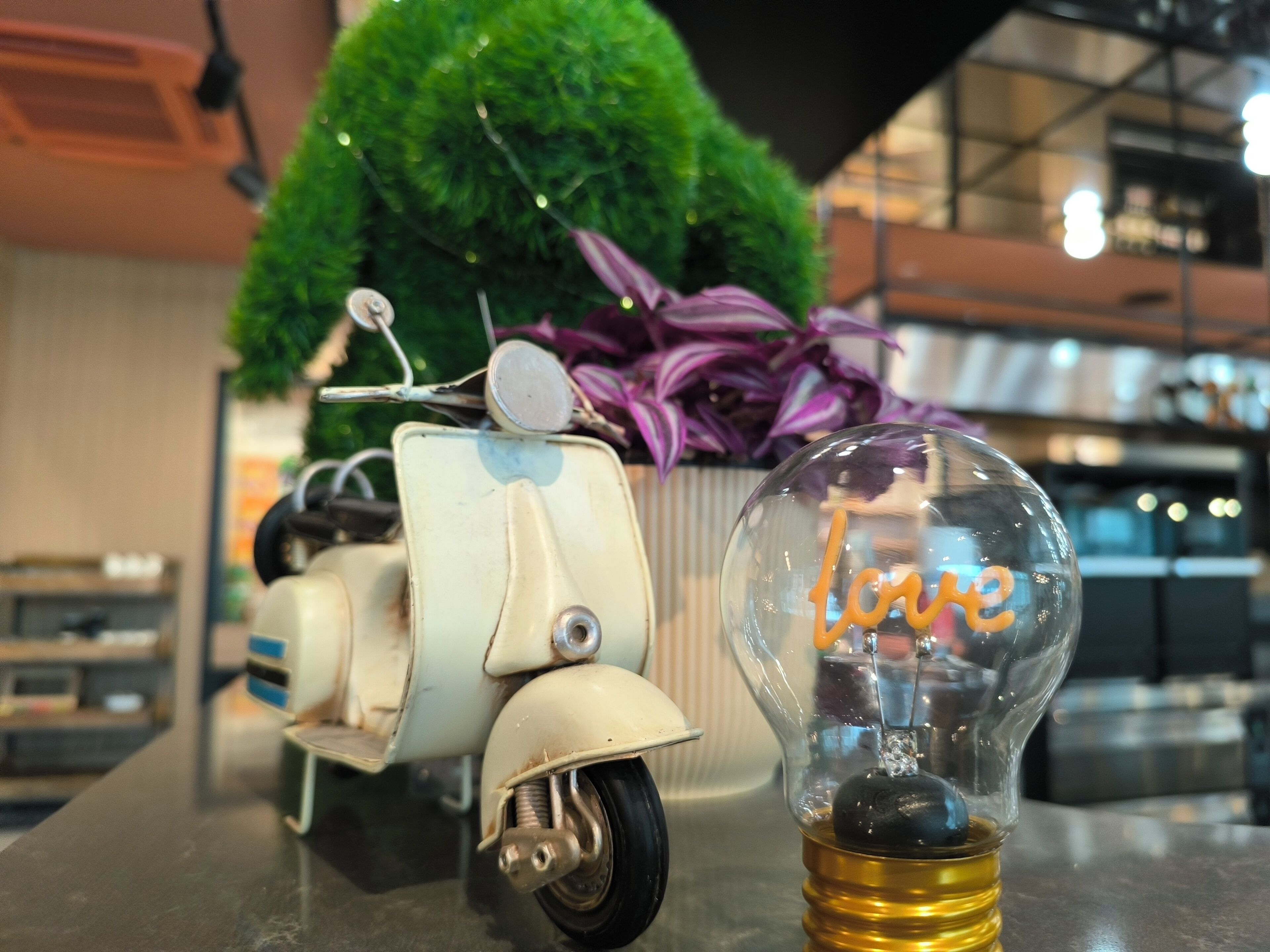 A vintage scooter and a light bulb with the word "love" inside it, placed on a table.