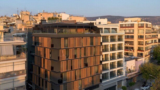 A multi-story building with a modern architectural design, featuring a mix of glass and wooden panel facades.