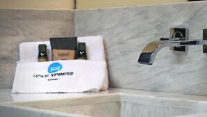 Een badkamer met een marmeren wastafel, een handdoek met de branding 'HOME YPRESS' en toiletartikelen.