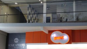 Een modern hotelinterieur met een glazen balustrade, een bordje voor restaurant 'el punt' en een 'HOMEXPRESS' bord.