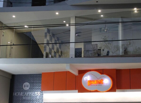 Un intérieur d’hôtel moderne avec une rambarde en verre, une enseigne pour le restaurant « el punt » et une enseigne « HOMEXPRESS ».