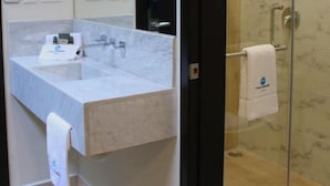 Een moderne badkamer met een marmeren wastafel, een douchecabine van glas en een handdoek aan de muur.