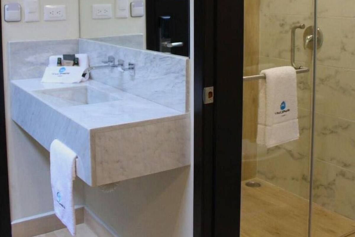 Um banheiro moderno com pia de mármore, box de vidro e uma toalha pendurada na parede.