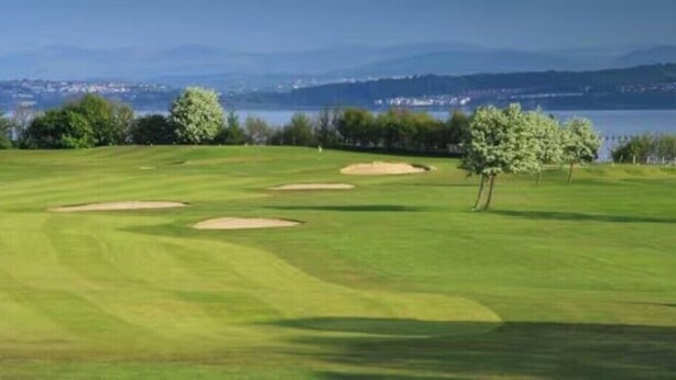 Ein Golfplatz mit Bunkern und einem See im Hintergrund.