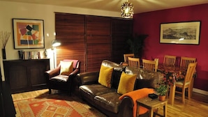 Ein Wohnzimmer mit Ledersofa, Esstisch aus Holz und Stühlen.