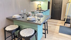 Cocina con una isla central, taburetes y comedor.