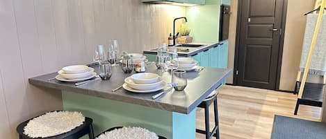A kitchen with a central island, stools, and a dining setup.