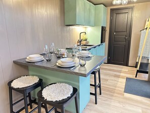 A kitchen with a central island, stools, and a dining setup.