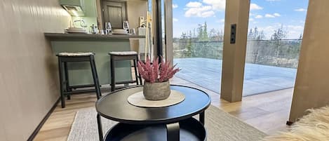 A modern kitchen with a dining area, a round table with a plant, and a view of the outdoors.