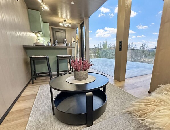 A modern kitchen with a dining area, a round table with a plant, and a view of the outdoors.