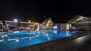 A nighttime swimming pool area with tiled flooring, lounge chairs, and a covered seating area. - h&Y chaweng (Koh Samui)