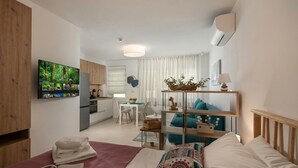 A modern hotel room with a bed, a TV, a desk, a chair, and a kitchen area. - Modern Studio Apartman 1 Desamani 975, Kostrena, Croatia (Kostrena)