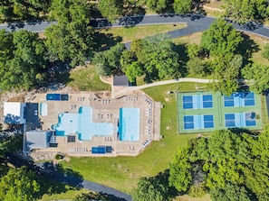 Ein Luftbild eines Resorts mit Schwimmbad, Tennisplätzen und einem Parkplatz.