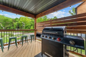 Un espace barbecue extérieur comprenant un gril, une terrasse en bois et des sièges.