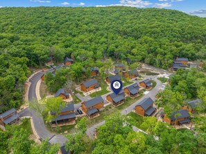 A residential area with multiple houses, roads, and a dense forest in the background. - Private Hot Tub Cabin Near Table Rock with Free Tickets & Indoor/Outdoor Community Pools (Hollister)
