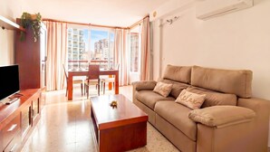 A modern living room with a sofa, a coffee table, a TV, and a dining area with a table and chairs. - Benidorm Levante Beach 11A, Benidorm, Spain (Benidorm)